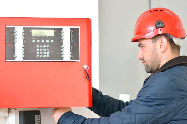 Young attractive electrical engineer at work with a red helmet on his head